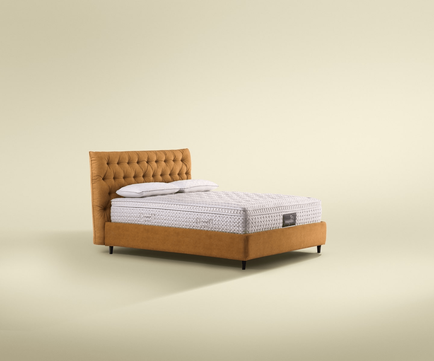 Magniflex queen-size bed mattress with a plush mustard headboard, displayed in a minimalist setting with a soft beige background.