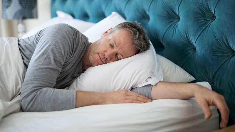 A man comfortably sleeping on a mattress with a pillow by Magniflex