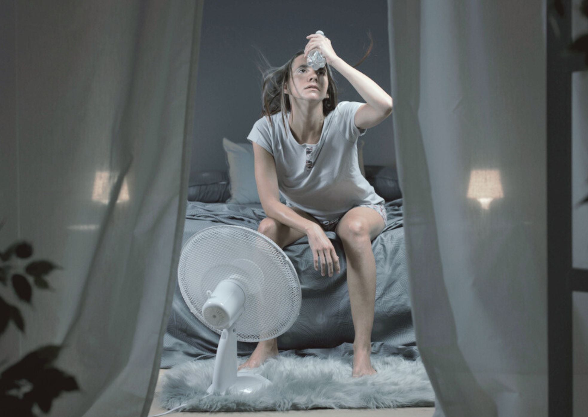 A woman in front of an electric fan to stay cool, reducing sweating while sleeping, and enjoying comfort from Magniflex in Dubai.