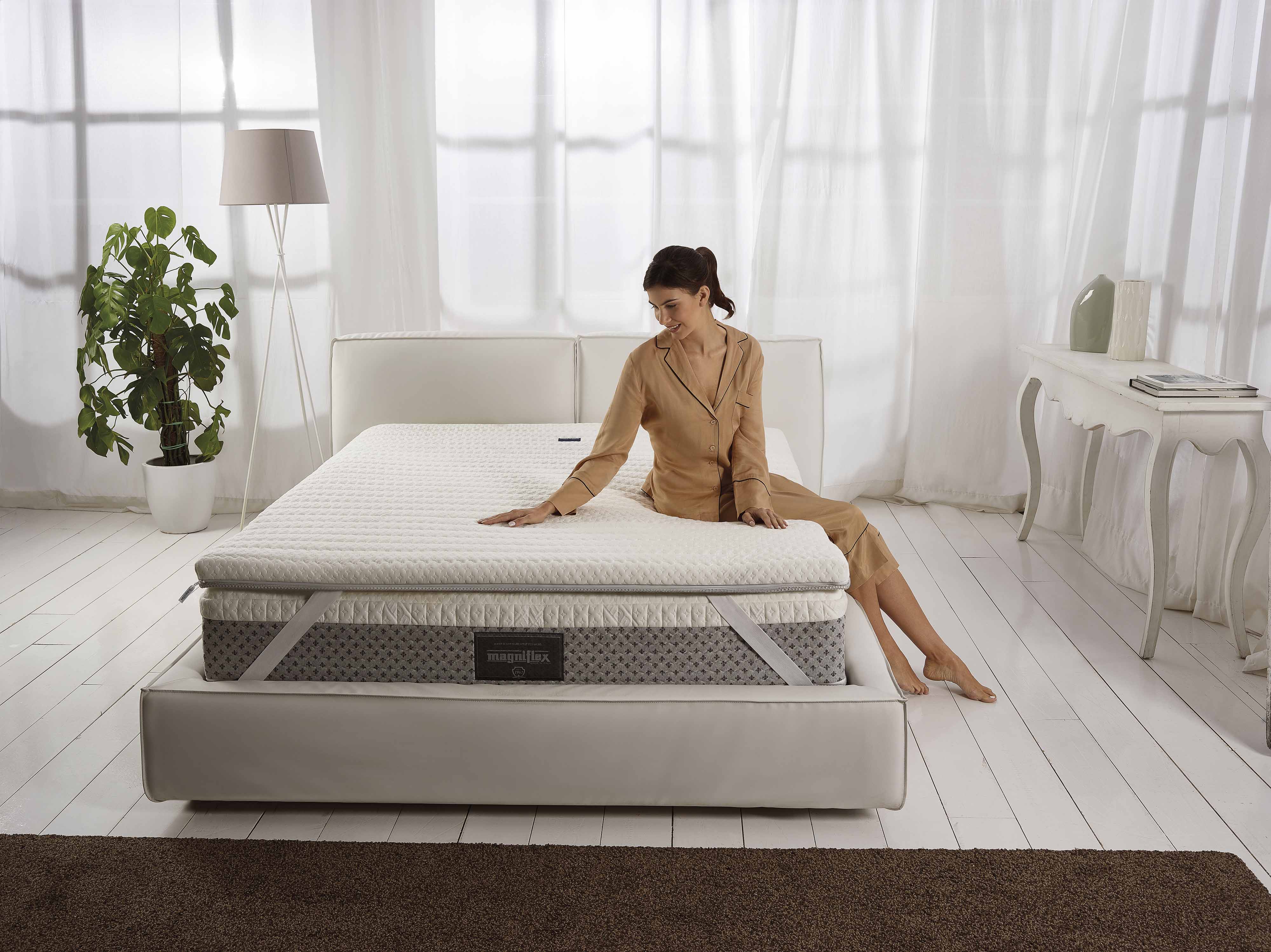 A woman sitting on a Magniflex mattress showcasing a neat and soft mattress