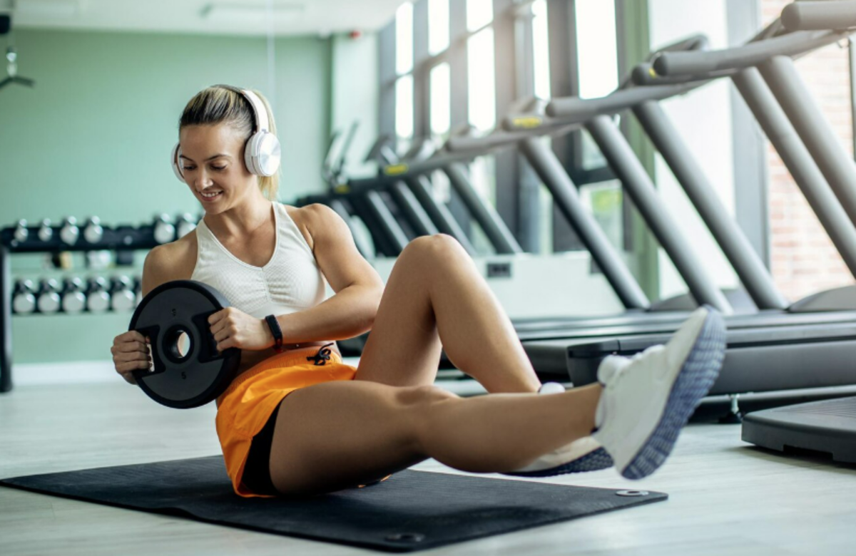 A woman performs a sit-up exercise in a gym setting in Dubai, focusing on her fitness routine, by Magniflex