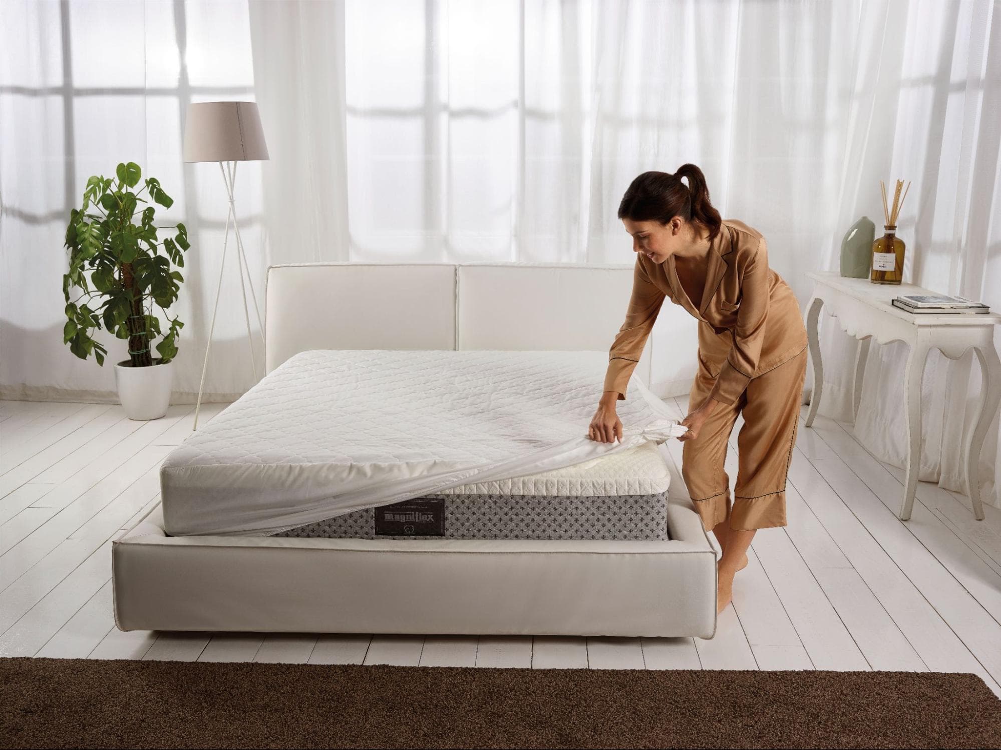 The guest room is being prepared for the holiday season with fresh linens, a mattress protector, and soft lighting accents.