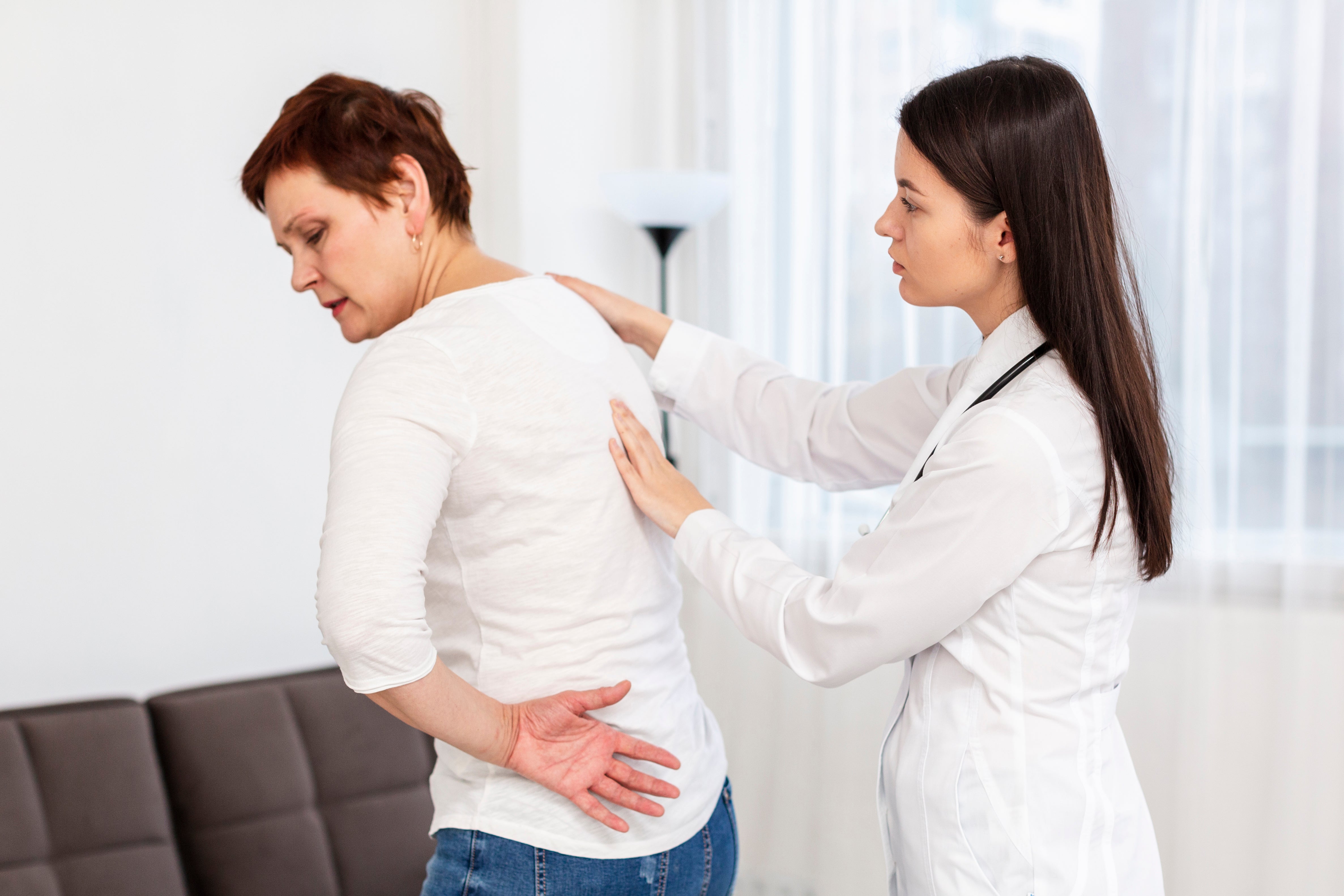 A doctor diagnosing an elderly woman with kyphosis.