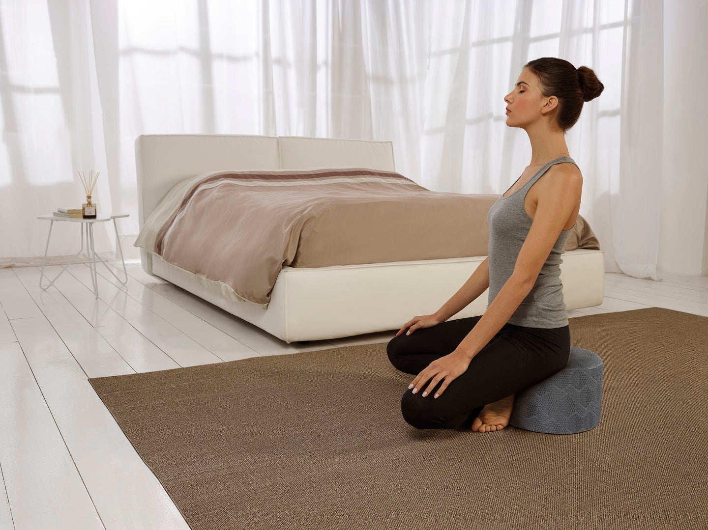 A woman experiencing back pain, now sitting upright comfortably on a mattress. 