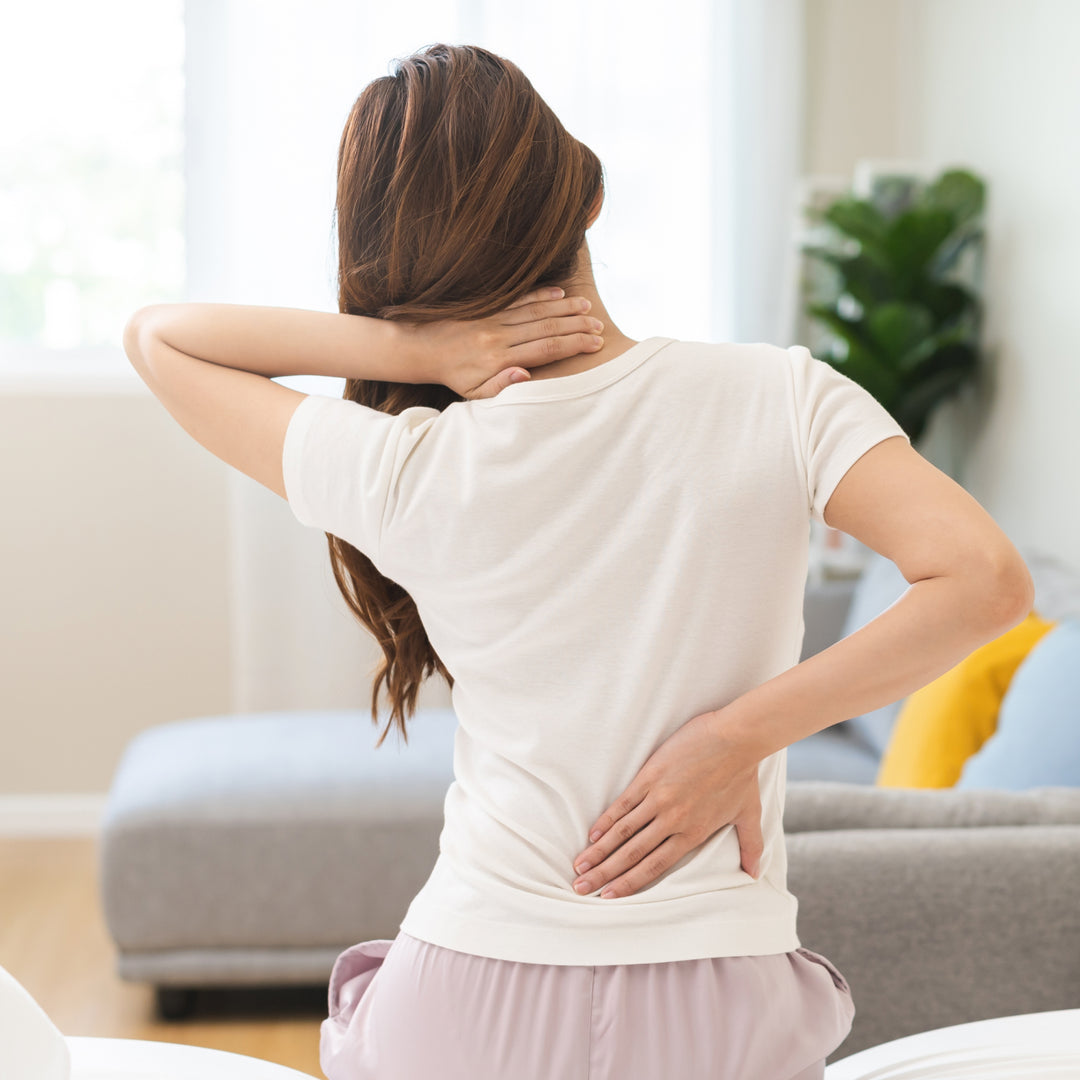 A woman holding her back due to back pain, which can be avoided using the right king size mattress, by Magniflex