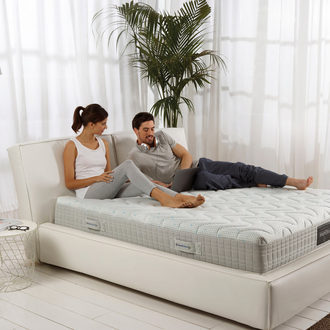 A couple sitting and lying down on a king size mattress, by Magniflex